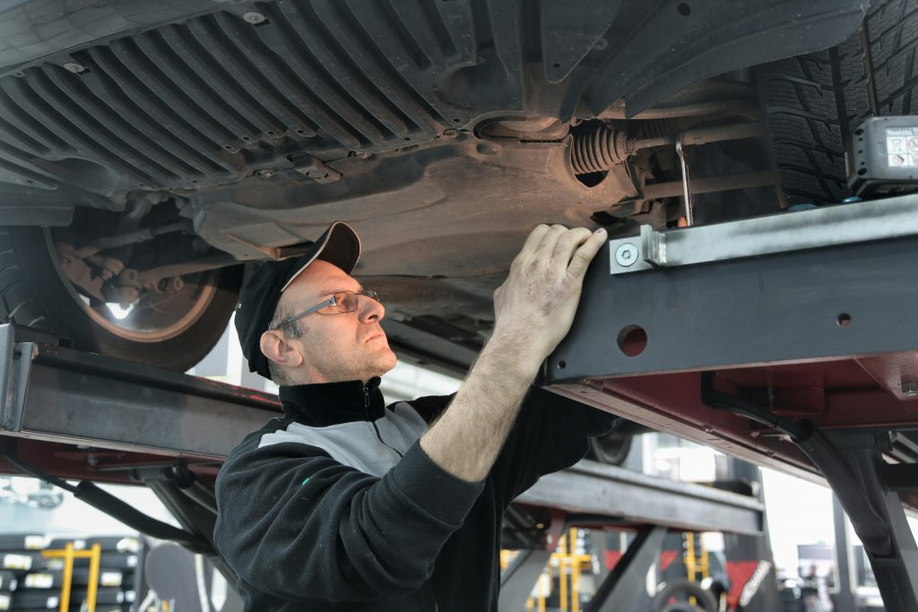 Machanic working on a car in a modern garage featuring digital signage